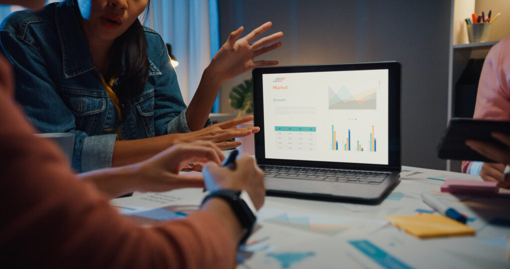 Marketing analysts discussing user interaction data and event tracking metrics displayed on a laptop.