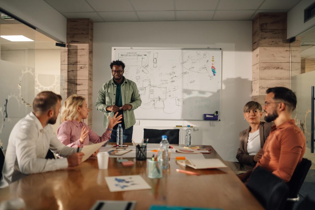 Marketing team discussing dynamic creative optimization (DCO) strategies during a brainstorming session in a modern office, with a whiteboard displaying campaign concepts.