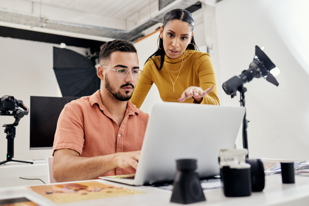 Two digital marketers analyzing eCPM data on a laptop to improve online ad revenue strategies.