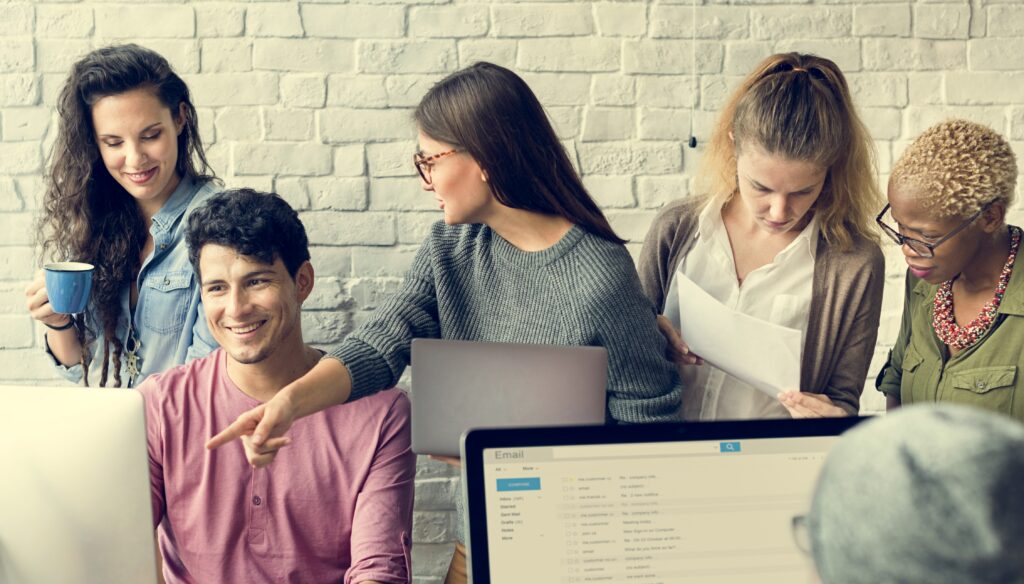 Marketing team collaborating on an e-blast email campaign, reviewing content and strategy on a computer screen.